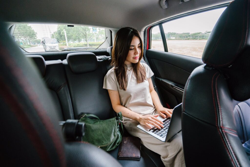 woman typing on laptop in car